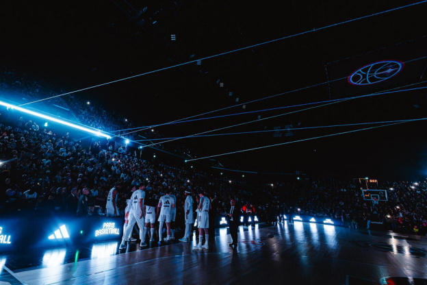 Entrée des joueurs sur le terrain avec un impressionnant jeu de lumières bleues et de lasers dans l'obscurité de l'Adidas Arena.