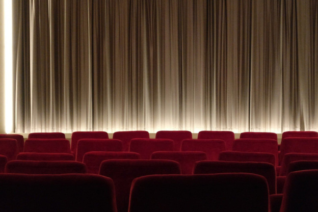 Salle de cinéma avec rangées de fauteuils rouges et écran fermé
