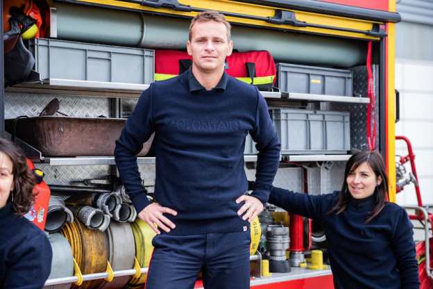 1083 présente son pull confectionné à partir de pulls de pompiers recyclés