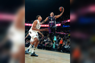 Action offensive d'un joueur du Paris Basketball s'envolant vers le panier sous la pression d'un défenseur du Real Madrid en EuroLeague.