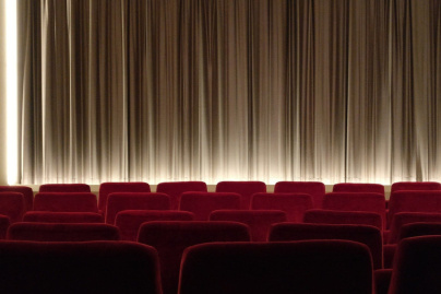 Salle de cinéma avec rangées de fauteuils rouges et écran fermé
