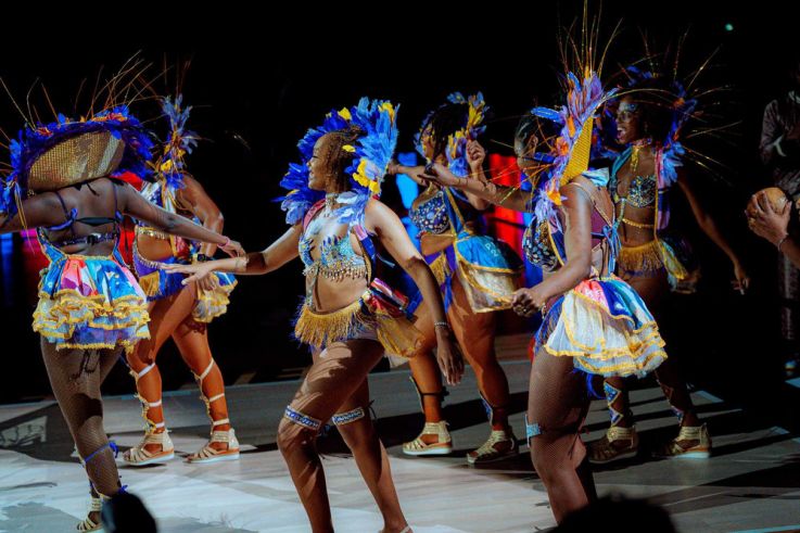 Danseuses en costumes de carnaval colorés assurant le show sur le parquet lors d'une soirée à thème organisée par le Paris Basketball.
