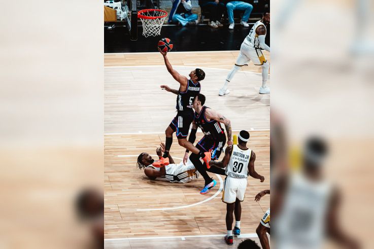 Justin Robinson du Paris Basketball en pleine action offensive, transperçant la défense de l'ASVEL en EuroLeague à l'Adidas Arena.
