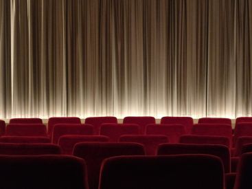 Salle de cinéma avec rangées de fauteuils rouges et écran fermé