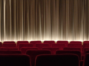 Salle de cinéma avec rangées de fauteuils rouges et écran fermé