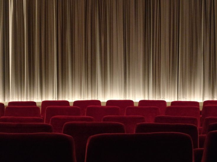 Salle de cinéma avec rangées de fauteuils rouges et écran fermé