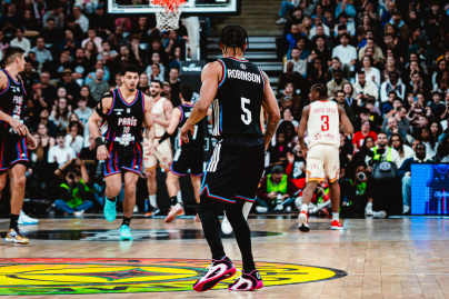 Campagne #36528 - Action de jeu intense en contre jour cinématique un joueur du Paris Basketball attaque le panier face à un défenseur adverse lors d'un match à l'adidas arena.