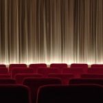 Salle de cinéma avec rangées de fauteuils rouges et écran fermé